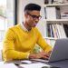 Successful african american businessman using computer at modern office. Happy creative young man feeling successful after receiving approval mail from client and working from home. Smiling student working and studying on computer sitting at desk.